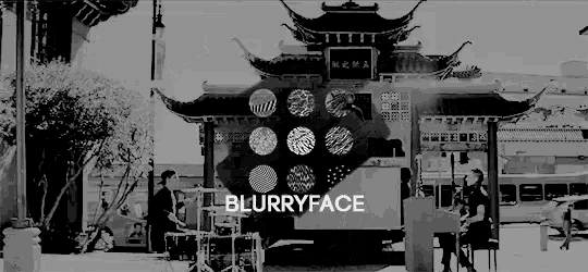 a black and white photo of a man playing drums in front of a chinese building with the words blurryface on the bottom .