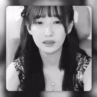 a black and white photo of a woman with a heart necklace