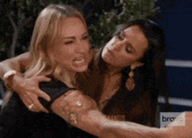 two women are hugging each other and one is making a face .
