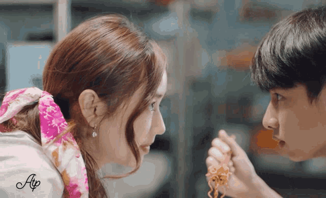 a man and a woman are looking at each other and the man is feeding the woman something