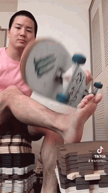 a man in a pink shirt is holding a skateboard in his hands