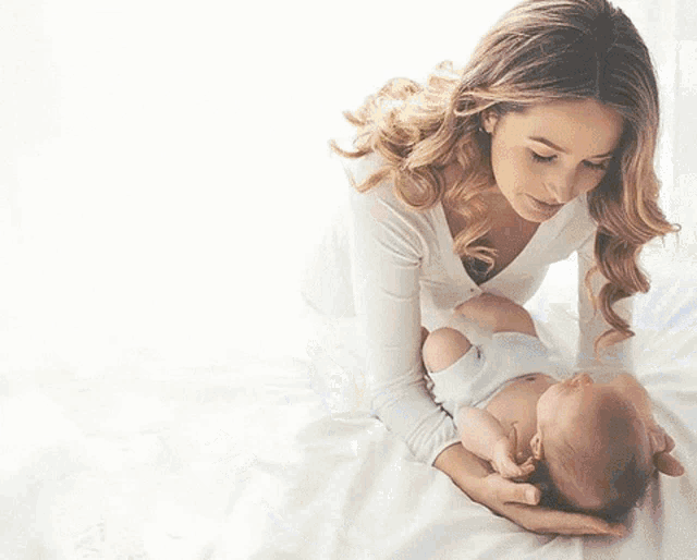 a woman is holding a baby wrapped in a white blanket .