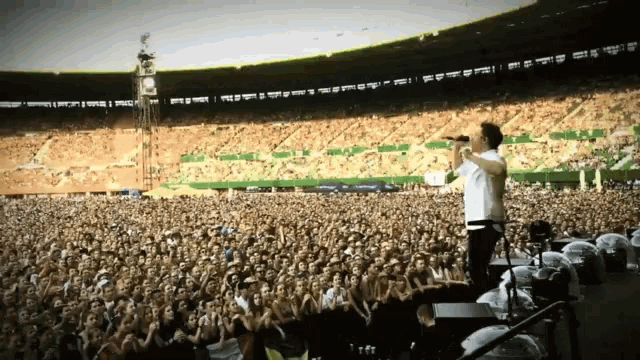 a man is singing into a microphone in front of a crowd at a concert