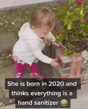 a little girl is standing in front of a christmas tree and a sign that says she is born in 2020