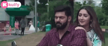 a man and a woman are riding a motorcycle in a park and the woman is hugging the man .