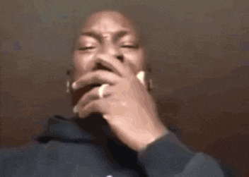 a man in a blue hoodie is smoking a cigarette with his hand on his mouth .