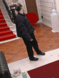 a person wearing headphones stands in front of a set of stairs