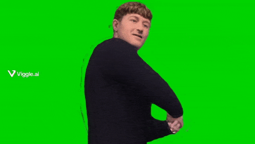 a man in a black sweater is sitting in a chair with his fist in the air on a green screen .