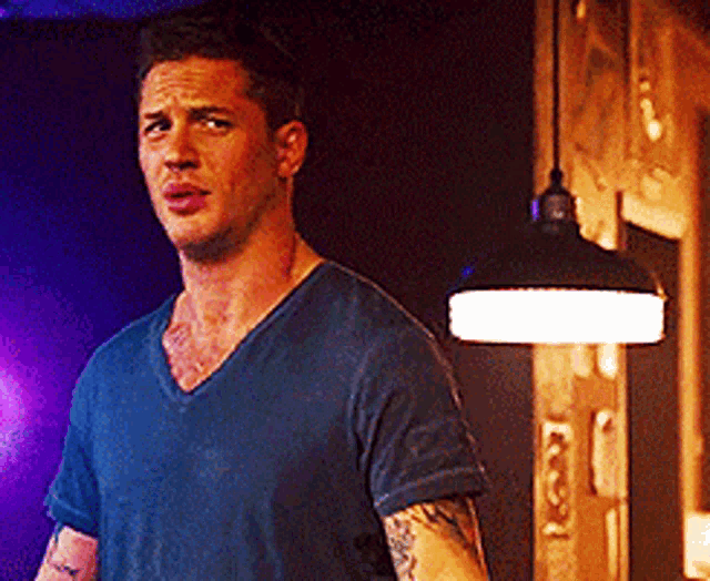 a man in a blue shirt is standing in front of a light .