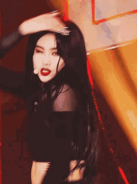 a woman with long black hair is dancing on a stage with a microphone .