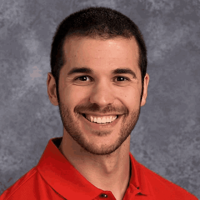 a man with a beard wearing a red shirt is smiling