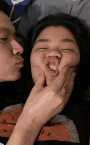 a man is kissing a woman on the cheek while she makes a funny face