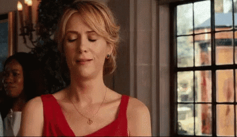 a woman in a red dress is sitting in front of a window and crying .