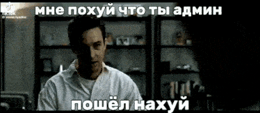a man in a white shirt is standing in front of a shelf and talking in a foreign language .