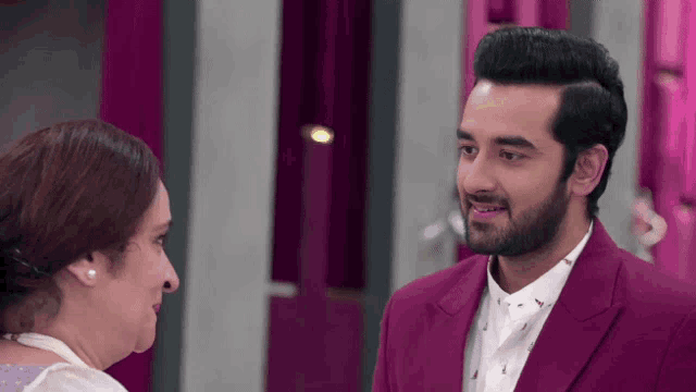 a man in a purple suit stands next to a woman in a white shirt