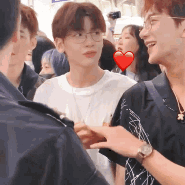 a man wearing glasses and a watch talks to another man