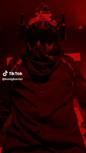 a man wearing a helmet and a scarf is standing in a dark room with tiktok written on the bottom right corner