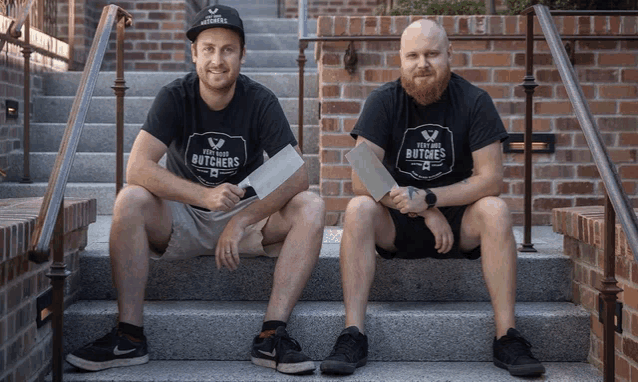 two men wearing shirts that say your local butchers are sitting on steps