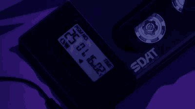 a dat device is sitting on a purple surface with a purple background .