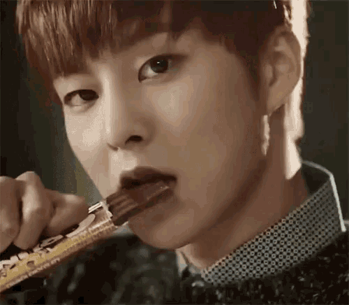 a close up of a young man eating a chocolate bar .