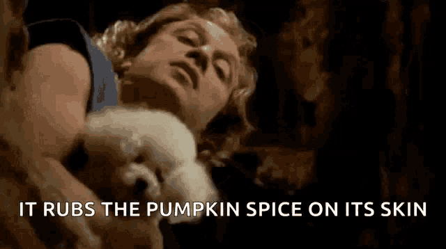 a man is holding a small white dog with the words it rubs the pumpkin spice on its skin