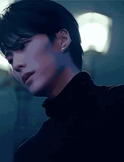 a close up of a man wearing a black turtleneck sweater and earrings .