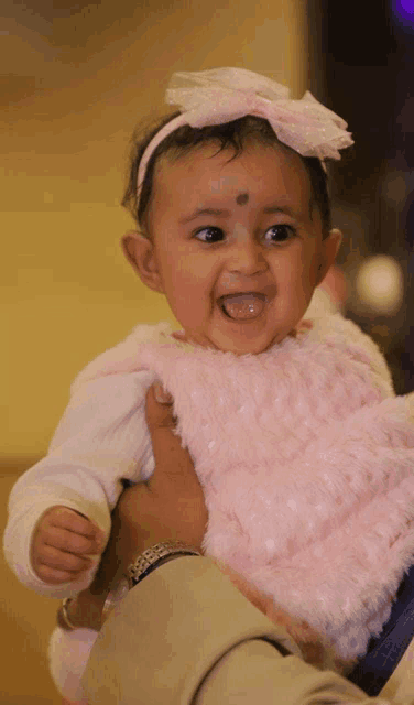 a baby with a bow on her head is being held by a man