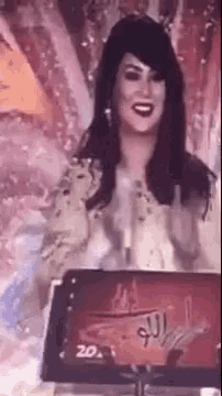 a woman is standing in front of a microphone and smiling while holding a sign .