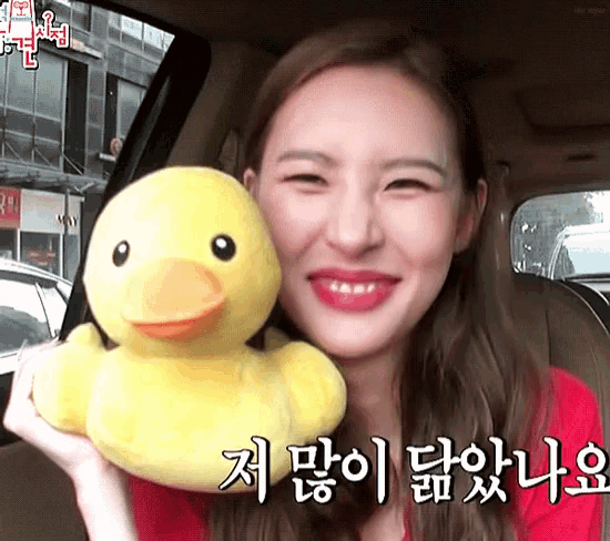 a woman in a red shirt is holding a yellow rubber duck and smiling
