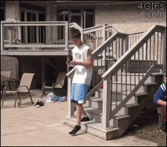 a man standing on a set of stairs looking at his phone with the website 4gifs.com in the corner