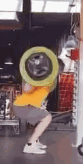 a person in a yellow shirt is squatting in front of a washing machine .