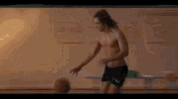 a shirtless man in shorts is kicking a basketball .