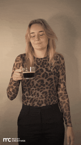 a woman wearing a leopard print shirt is holding a cup of coffee