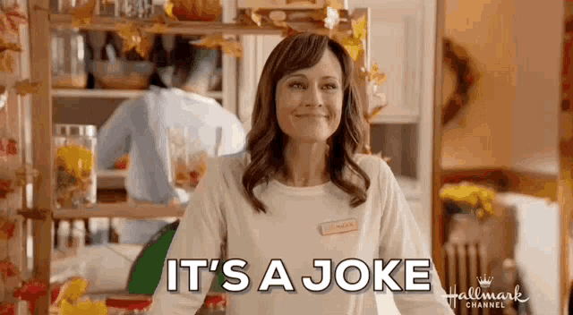 a woman is smiling in a kitchen with the words `` it 's a joke '' written above her .
