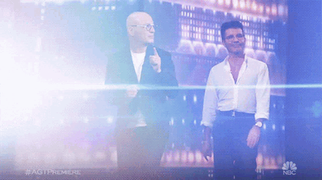 two men standing next to each other on a stage with the nbc logo in the background