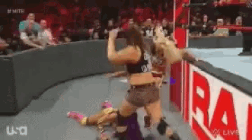 two women are wrestling in a ring with a sign that says raw on it
