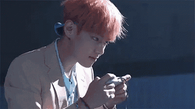 a young man with red hair is playing a video game on a cell phone .