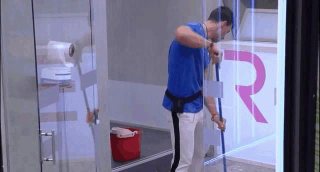 a man is cleaning a glass door with a mop and bucket