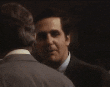 a man in a suit talks to another man in a suit