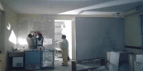a group of men are standing in a room with a ladder