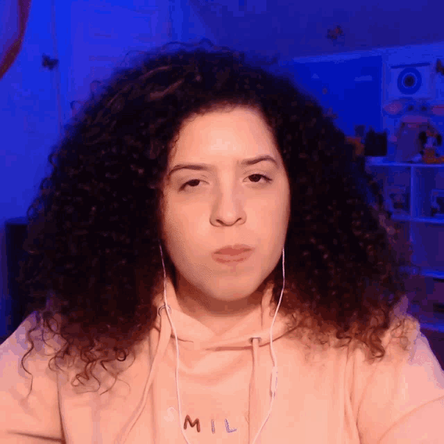 a woman with curly hair wearing a pink hoodie that says smil on it