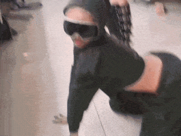 a person wearing a hoodie and goggles is kneeling down on the floor