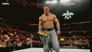 a man in a wrestling ring holds a championship belt