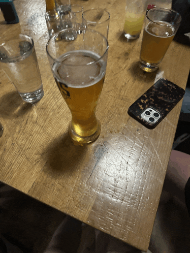 a glass of beer with the letter s on it sits on a wooden table