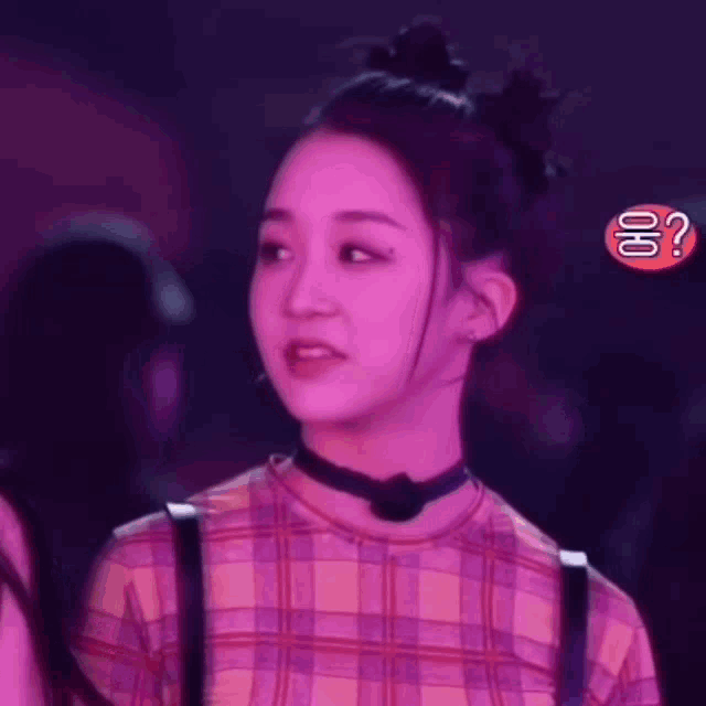a woman in a plaid shirt has a choker around her neck and a question mark in the background