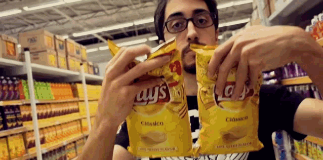 a man holding two bags of lays chips in his hands