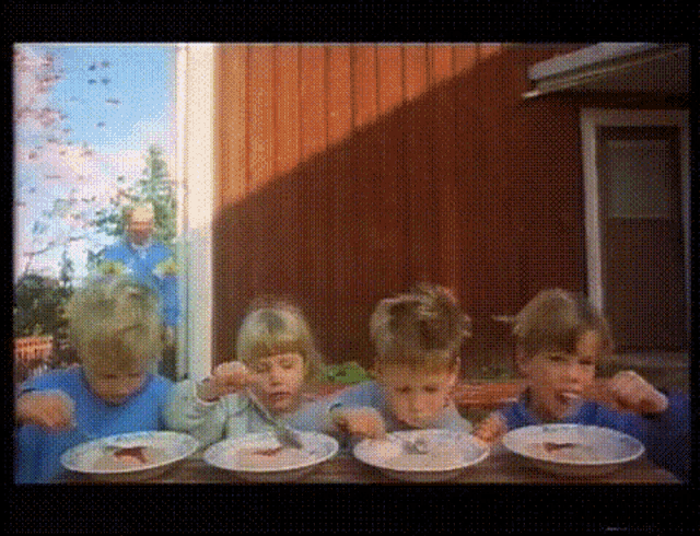 a group of children are sitting at a table eating from bowls