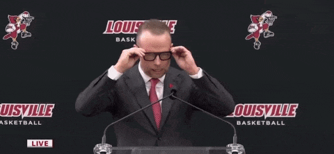 a man in a suit and tie is speaking into a microphone .