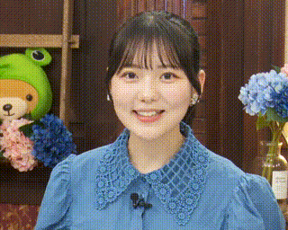 a woman in a blue shirt is smiling in front of a green stuffed animal .