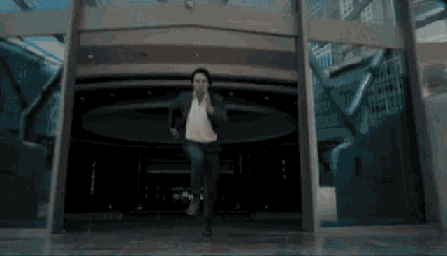 a man in a suit and white shirt is walking out of a building